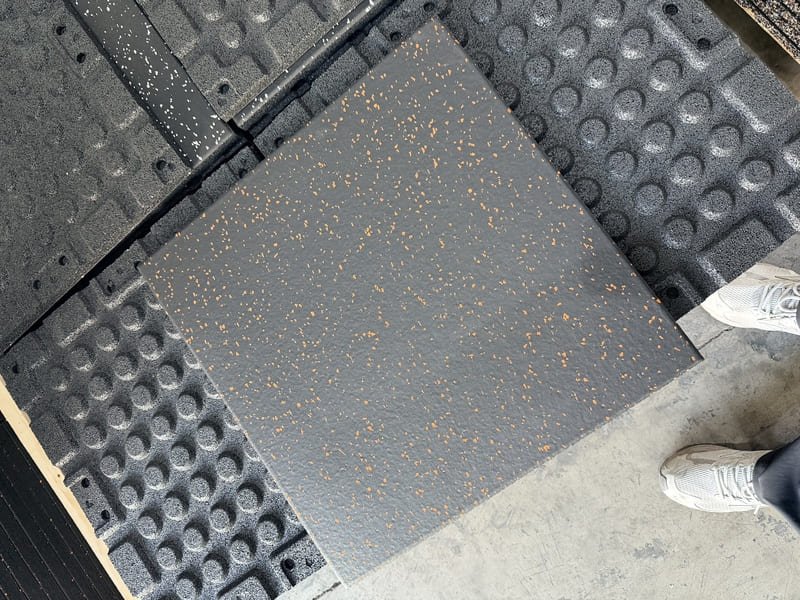 Staff using a wet-dry vacuum to extract cleaning solution from gym tiles